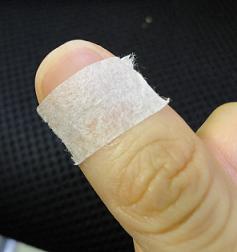 爪の付け根に白テープを貼った親指